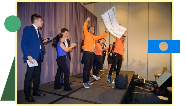 Pessoas em um palco levantando um grande cheque, demonstrando alegria e união em uma conquista significativa.